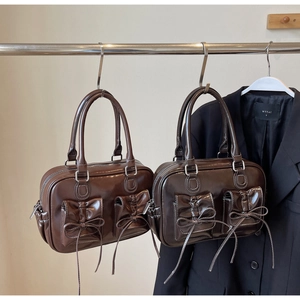 Detail of dark brown vintage handbag with glossy finish and ribbon bow accents