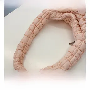 Detail of pink quilted cloud bag featuring soft ruched fabric and silver zipper closure