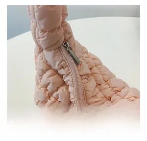 Detail of smooth silver zipper on pink quilted crossbody bag with puffer nylon texture