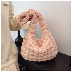 Detail of light pink quilted cloud crossbody bag with soft padded texture and rhombus pattern