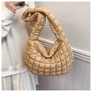 Detailed view of beige quilted cloud bag texture with metal zipper and soft fabric