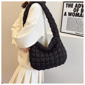 Detail of black quilted cloud bag with padded square texture and wide shoulder strap