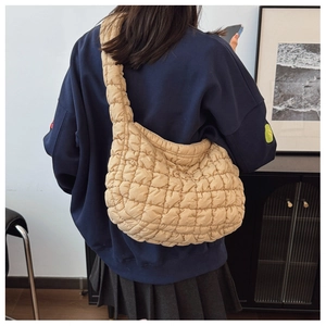 Detail of beige quilted dumpling bag texture and crossbody fit on a person