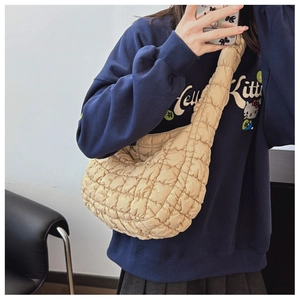 Detail view of large quilted cloud bag featuring soft beige crossbody moon shape design