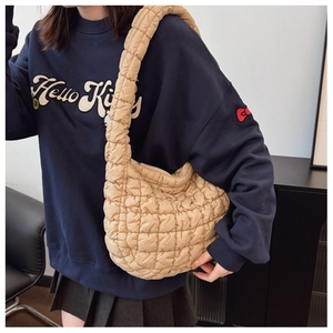 Detail of light beige quilted cloud bag texture and wide shoulder strap on model