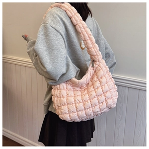 Close-up of pink quilted puffy bag showing diamond stitching and wide shoulder strap