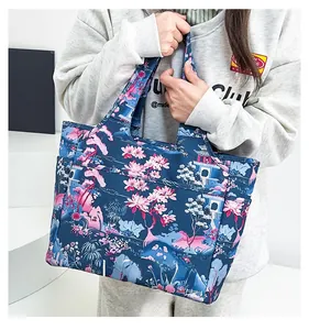 Dettaglio di una borsa tote in Oxford con stampa floreale blu scuro e manici robusti