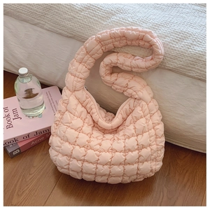 Detail of light pink cloud pleated quilted bag featuring bubble texture on white bed