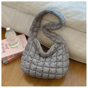 Close-up of grey quilted puff shoulder bag with soft cloud texture and zipper detail
