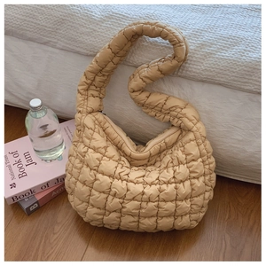 Macro shot of quilted beige cloud hobo bag with padded texture and soft grid stitching