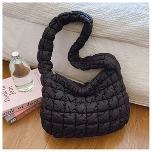 Macro view of black quilted cloud bag showing soft puff texture and silver zipper detail