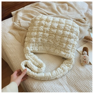 Detail of off-white cloud quilted bag showing soft bubble texture and matching zipper