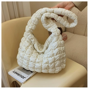 Close-up of white cloud bag showing quilted popcorn texture and wide shoulder strap