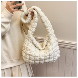 Detail of white quilted cloud bag featuring soft padded texture and wide shoulder strap