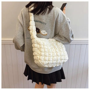 Rear view of model wearing a white quilted cloud crossbody bag with soft padded texture