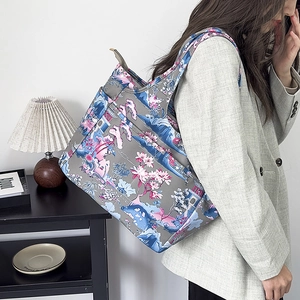 Borsa tote in oxford con stampa floreale indossata da una modella in abito grigio