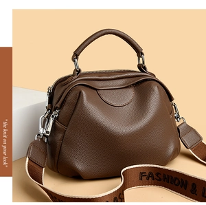 Nahaufnahme der braunen Muscheltasche aus Leder mit breitem Modegurt und Silber-Reißverschlüssen