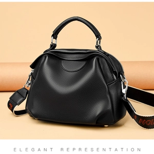 Detail der schwarzen Handtasche mit Lychee-Prägung und jacquardgewebtem breitem Schultergurt