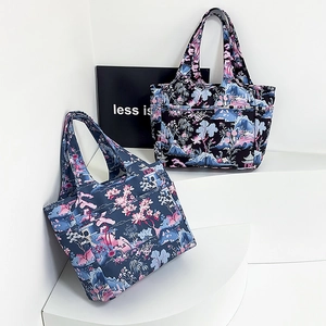 Dettaglio di borse tote in Oxford con motivi floreali su gradini geometrici bianchi