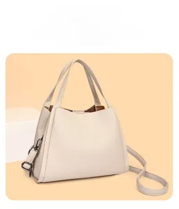 Detail view of cream-white pebble grain leather bucket bag with top handles and strap
