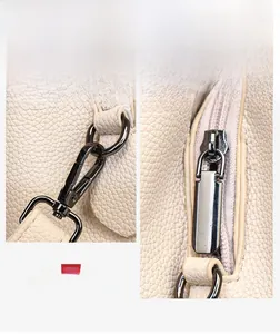 Detailed shot of gunmetal hardware with lobster clasp and zipper on beige leather bag