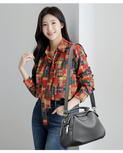 Detailansicht der grauen Leder-Muscheltasche mit Riemen am Model im karierten Hemd
