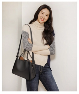 Black lychee leather bucket bag detail with textured handle and brown inner lining