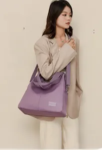 Lavender waterproof nylon tote bag shown in a stylish crossbody carry style on a model