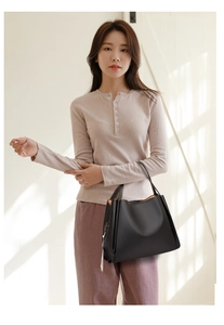 Close-up of black lychee grain leather tote bag with contrasting tan lining and dual handles