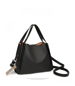 Detail of black lychee grain leather tote bag with dual handles and silver metal tag