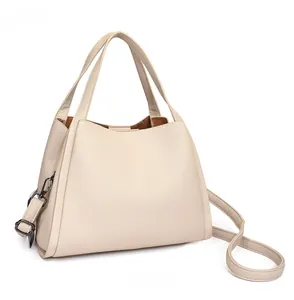 Detail view of beige lychee pattern leather bucket bag with dual handles and strap