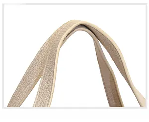 Detailed macro of wide beige lychee leather handle on minimalist bucket handbag