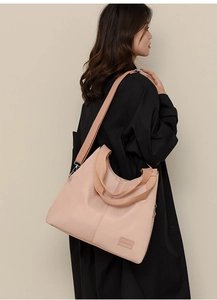 Detail of light pink waterproof nylon tote bag with versatile shoulder straps on model