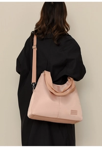 Detail view of pink waterproof nylon tote bag with wide shoulder strap on model back