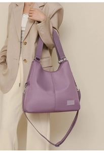 Detail of purple waterproof nylon tote bag with wide shoulder strap and brand label
