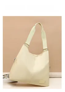 Detail of a beige nylon tote bag featuring wide fabric straps and adjustable silver buckle