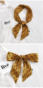 Vue détaillée du foulard étroit en soie jaune gingembre avec motifs de lettres D noires