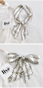 Détail d'un foulard étroit blanc à motif chaîne noué en nœud sur un col de chemise blanc
