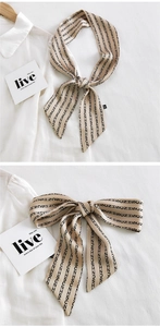 Détail d'un foulard étroit en satin beige à imprimé lettres sur une chemise