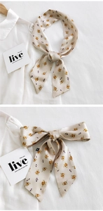 Détail d'un foulard en soie fleurie crème noué en boucle sur un col de chemise