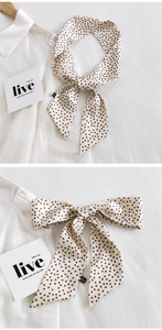 Détail d'un foulard étroit crème à motif cœurs marrons noué de façon élégante