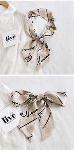 Détail d'un foulard en soie beige avec motif calèche noir et calligraphie d'art