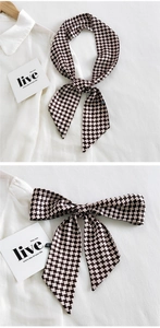 Détail d'un foulard en soie pied-de-poule noué en nœud sur une chemise blanche