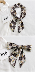 Gros plan d'un foulard étroit à fleurs noué en nœud sur un col de chemise blanc