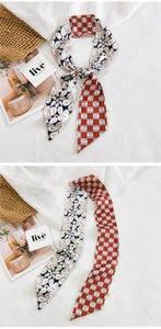 Détail d'un foulard étroit en soie avec motifs paisley et revers à carreaux sur tissu blanc