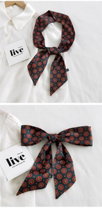 Détail d'un foulard étroit vert foncé avec motifs floraux sur une chemise blanche