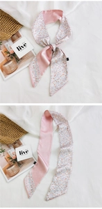 Détail d'un foulard en soie à fleurs noué en boucle sur un tissu blanc texturé élégant
