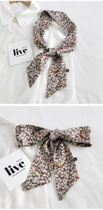 Vue détaillée d'un foulard étroit à fleurs noué en boucle sur un col de chemise blanc