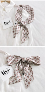 Détail d'un foulard étroit à motif géométrique noué sur le col d'une chemise