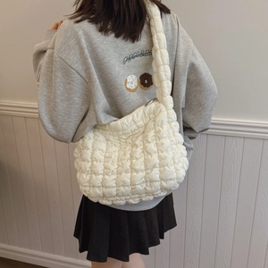 Minimalist beige quilted cloud crossbody bag with soft puffer texture and wide shoulder strap